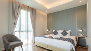 A modern hotel room with a large bed, a chair, and a nightstand with a lamp. - Lanna Bonita Boutique Hotel (Chiang Mai)