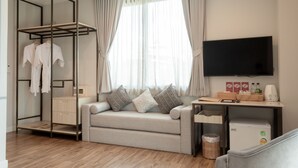 A modern hotel room with a sofa, a TV, a wardrobe, and a small kitchenette. - Lanna Bonita Boutique Hotel (Chiang Mai)