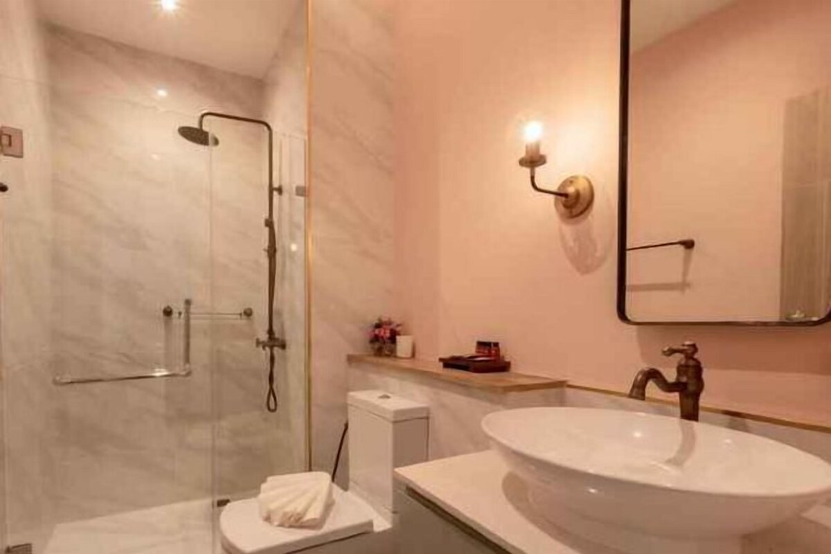 A modern bathroom with a marble shower, a white sink, and a large mirror.