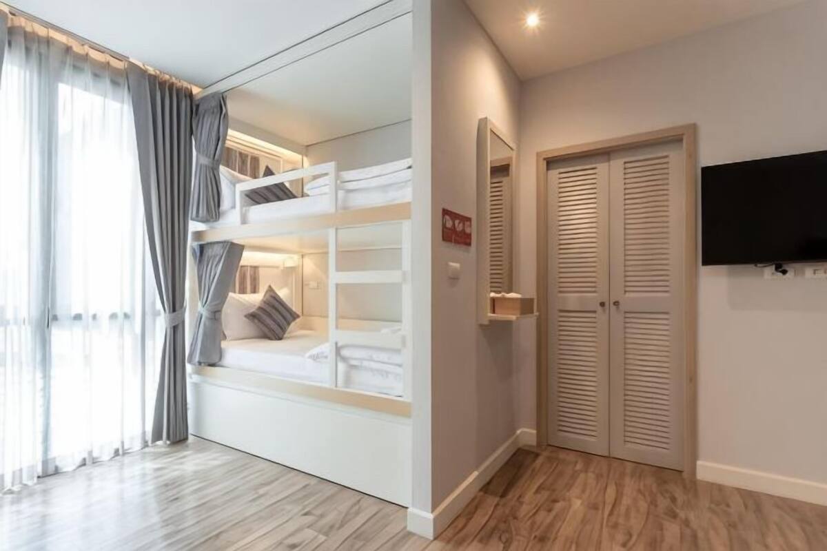 A bedroom with bunk beds, a wardrobe, a television, and a mirror.