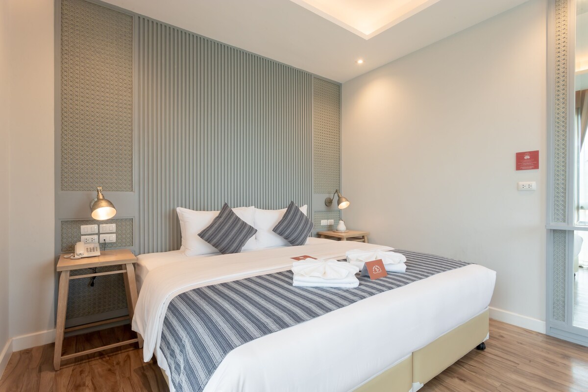Ein modernes Hotelzimmer mit einem großen Bett, Nachttischen und Blick ins Freie.