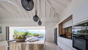 A modern kitchen with a wooden island, stainless steel appliances, and a view of the outdoors. - Villa prestige Sea view & beach access path (Saint-François)