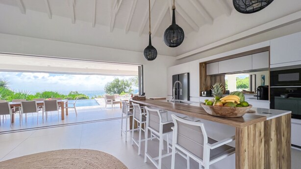 A modern kitchen with a large island, bar stools, and a view of the outdoors. - Villa prestige Sea view & beach access path (Saint-François)