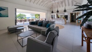A spacious living area with a high ceiling, a sofa, a coffee table, and a view of the outdoors. - Villa prestige Sea view & beach access path (Saint-François)