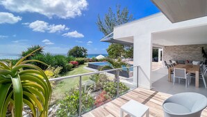 A modern outdoor patio with a pool, seating area, and a view of the sea. - Villa prestige Sea view & beach access path (Saint-François)