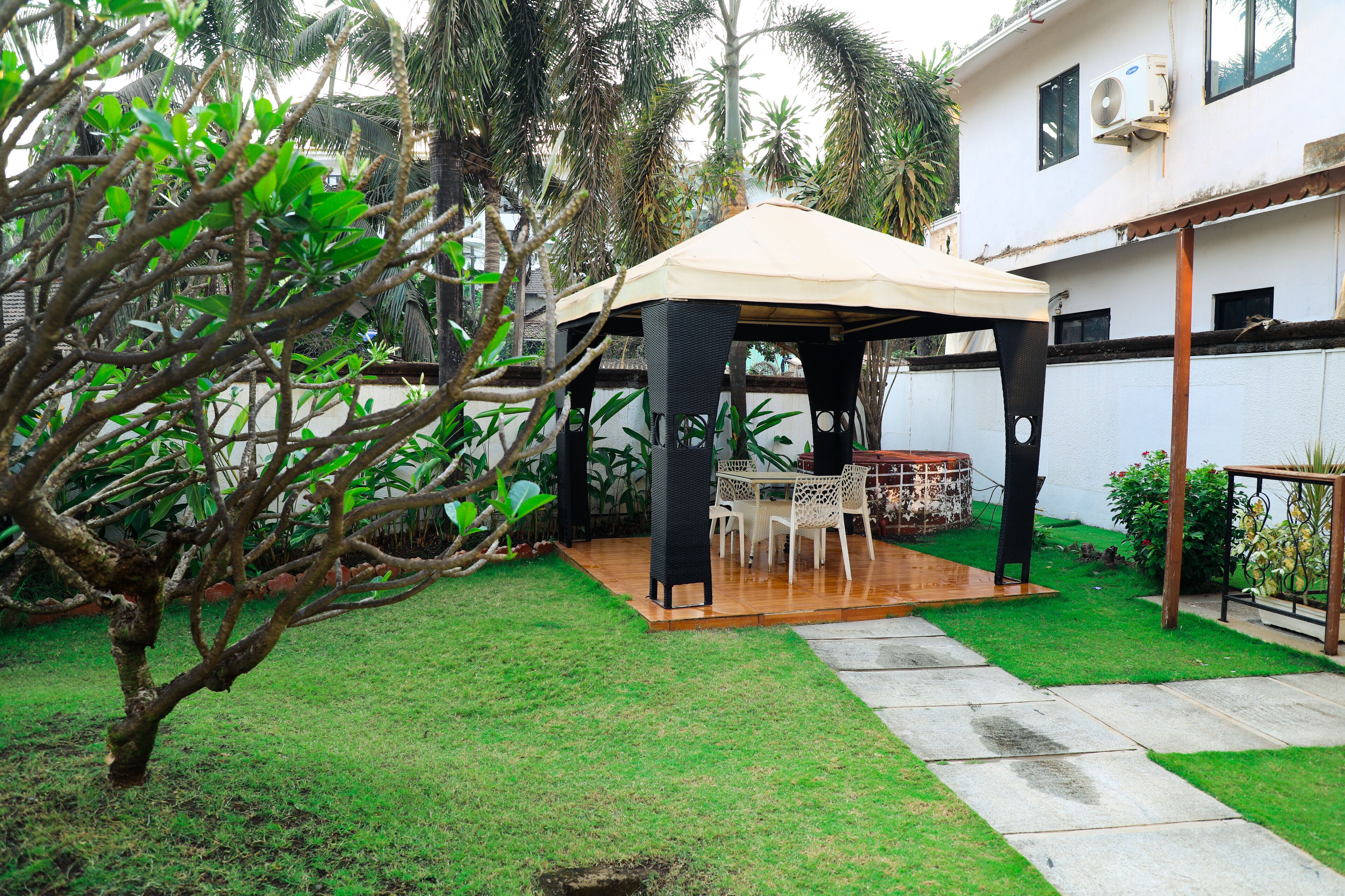 A covered patio area with a table and chairs, surrounded by a well-maintained lawn and palm trees.