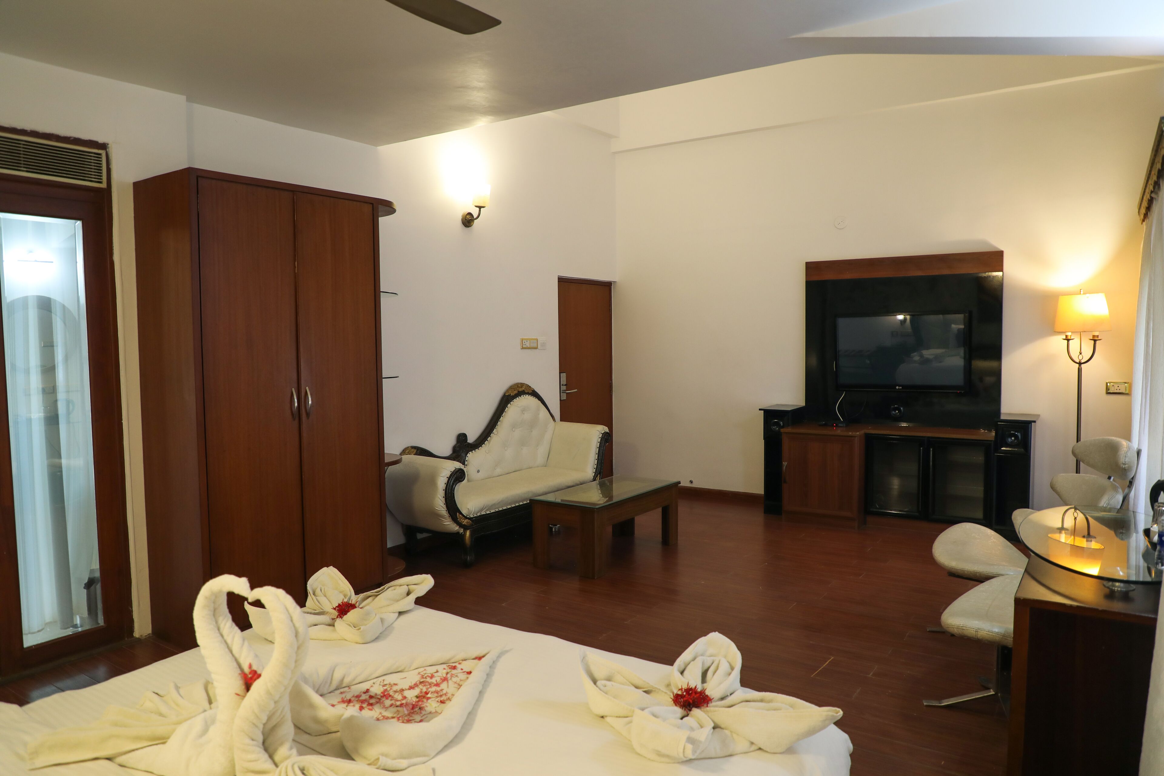 A hotel room with a bed, a sofa, a TV, a desk, and a wardrobe.