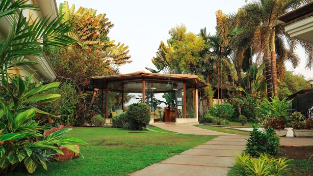 A garden with a covered seating area, a pathway, and various plants. - White Pearl Suites by Rosetum (Calangute)