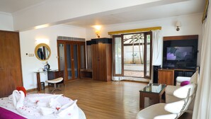 A hotel room with a bed, a TV, a desk, and a chair. - White Pearl Suites by Rosetum (Calangute)