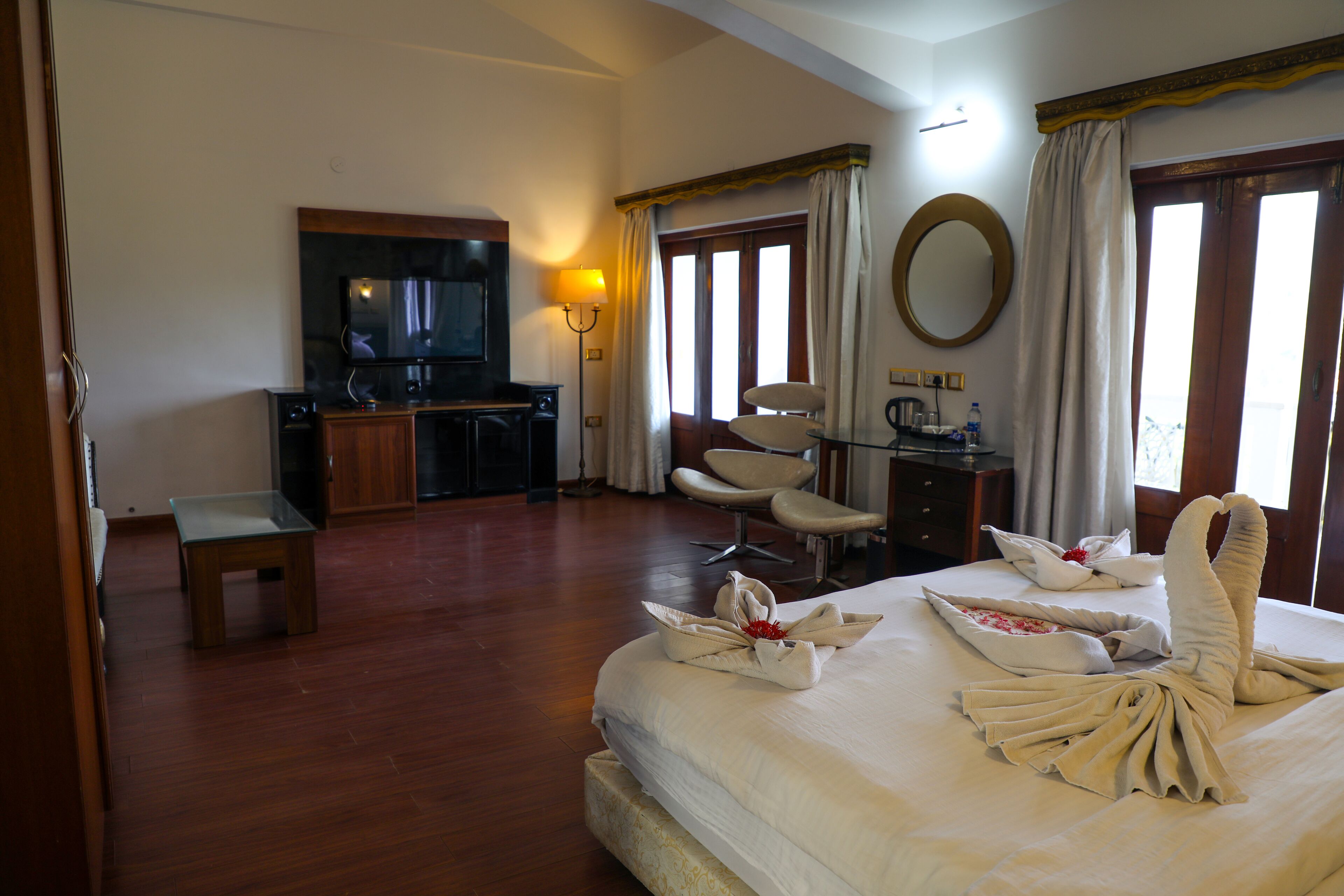 A hotel room with a bed, a desk, a chair, a television, and a mirror.