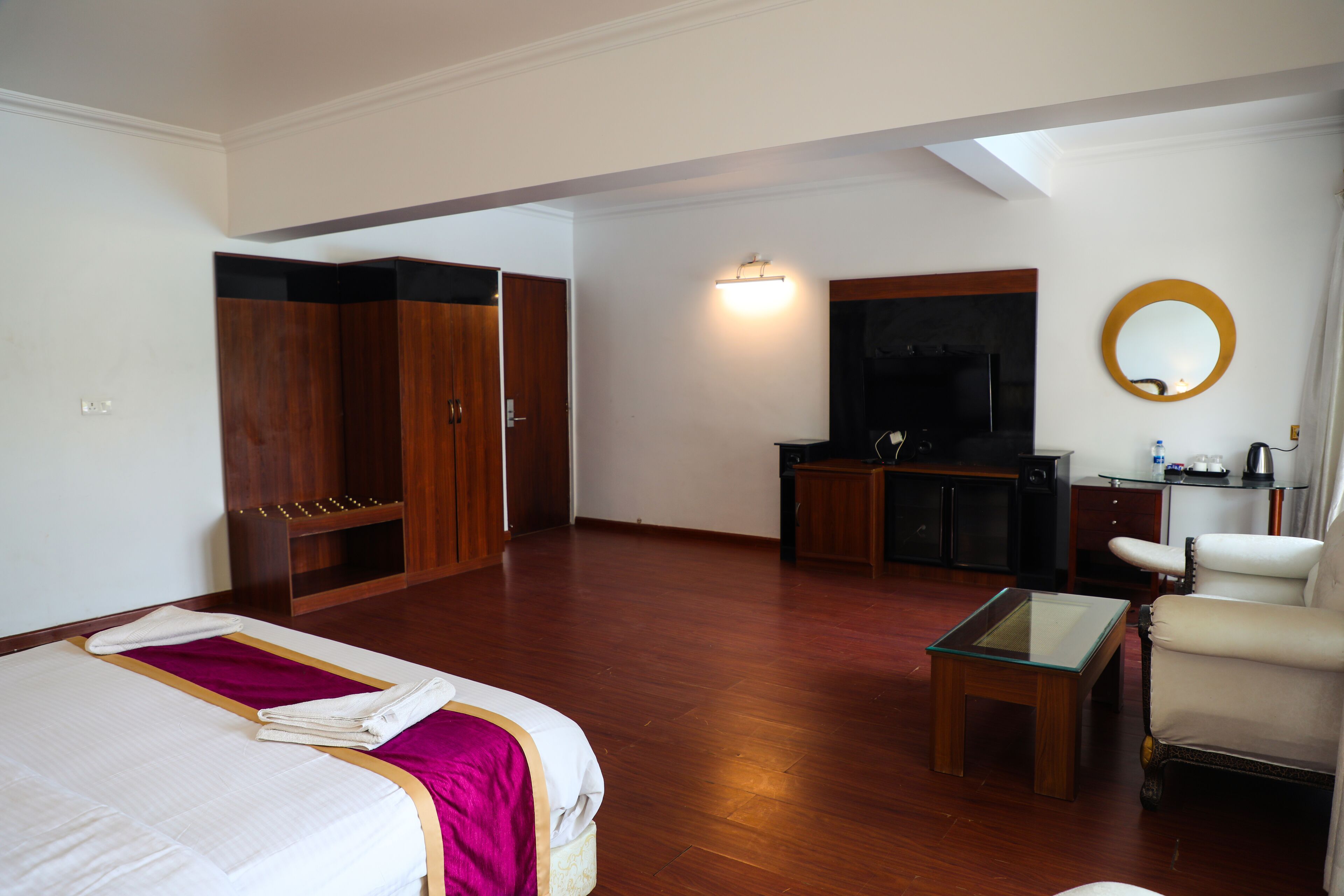 Une chambre d’hôtel comprenant un lit, un bureau, une chaise, une armoire et un miroir.