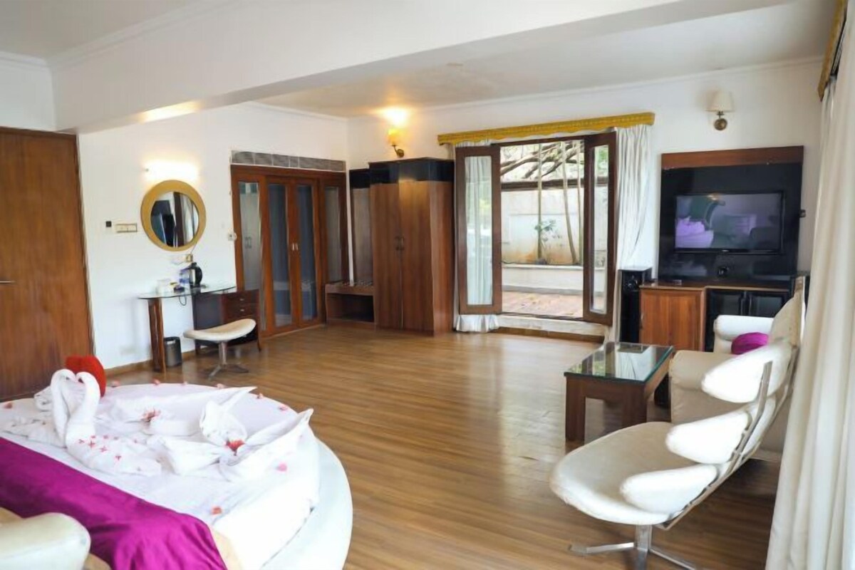 A hotel room with a bed, a TV, a desk, and a chair.