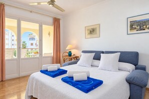 A hotel room with a bed, a nightstand, a lamp, and a view of the outside. - Classic apartment  with communal pool in Javea, Costa Blanca, Spain for 4 persons (Javea)