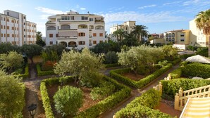 A landscaped garden with a central pathway, surrounded by neatly trimmed hedges and trees. - Classic apartment  with communal pool in Javea, Costa Blanca, Spain for 4 persons (Javea)