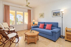 A living room with a blue sofa, wicker chairs, a coffee table, and a floor lamp. - Classic apartment  with communal pool in Javea, Costa Blanca, Spain for 4 persons (Javea)