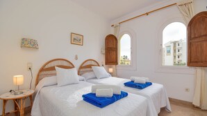 A hotel room with two beds, a small table with a lamp, and a view of the city through arched windows. - Classic apartment  with communal pool in Javea, Costa Blanca, Spain for 4 persons (Javea)