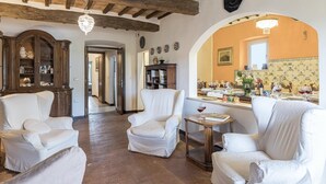 Un accogliente soggiorno con poltrone bianche, un mobiletto in legno e un'area pranzo con la tavola apparecchiata per un pasto.
