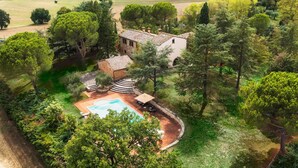 Une maison avec une piscine, entourée d’arbres et d’un jardin.