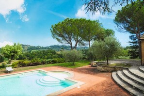 A swimming pool with a stone deck, surrounded by lush greenery and trees, with a view of rolling hills in the background. - Fonte Pinella 8 in Chiusi (Chiusi)