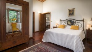 Une chambre avec un grand miroir, un lit avec deux oreillers, une table de chevet et une chaise.