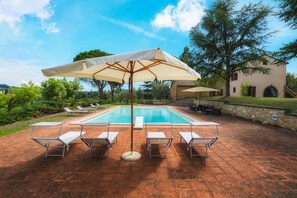 A swimming pool with four sun loungers and a large umbrella, surrounded by a stone patio and a building with arched windows. - Fonte Pinella 8 in Chiusi (Chiusi)
