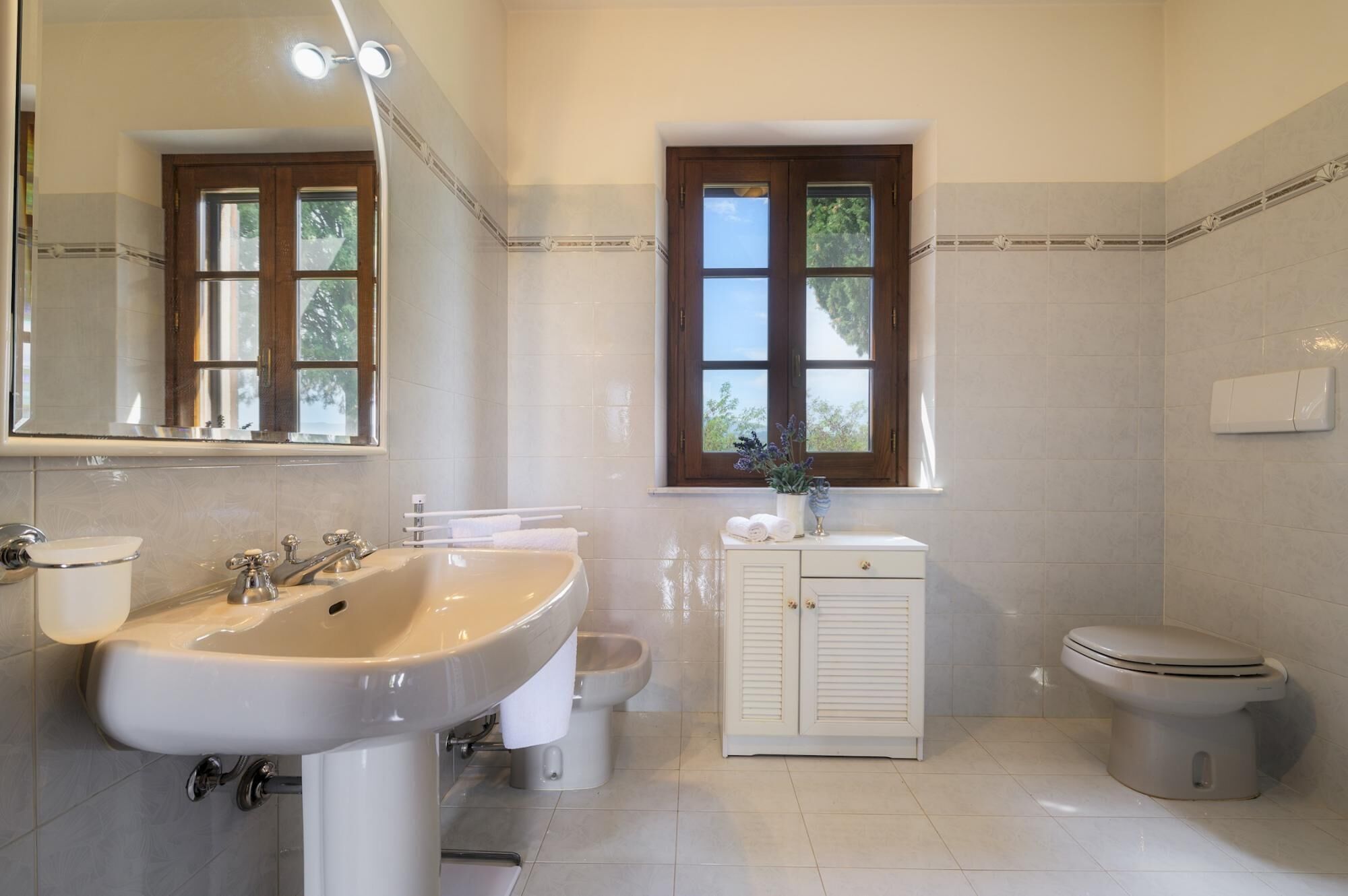 Une salle de bain avec un lavabo, des toilettes et une fenêtre.