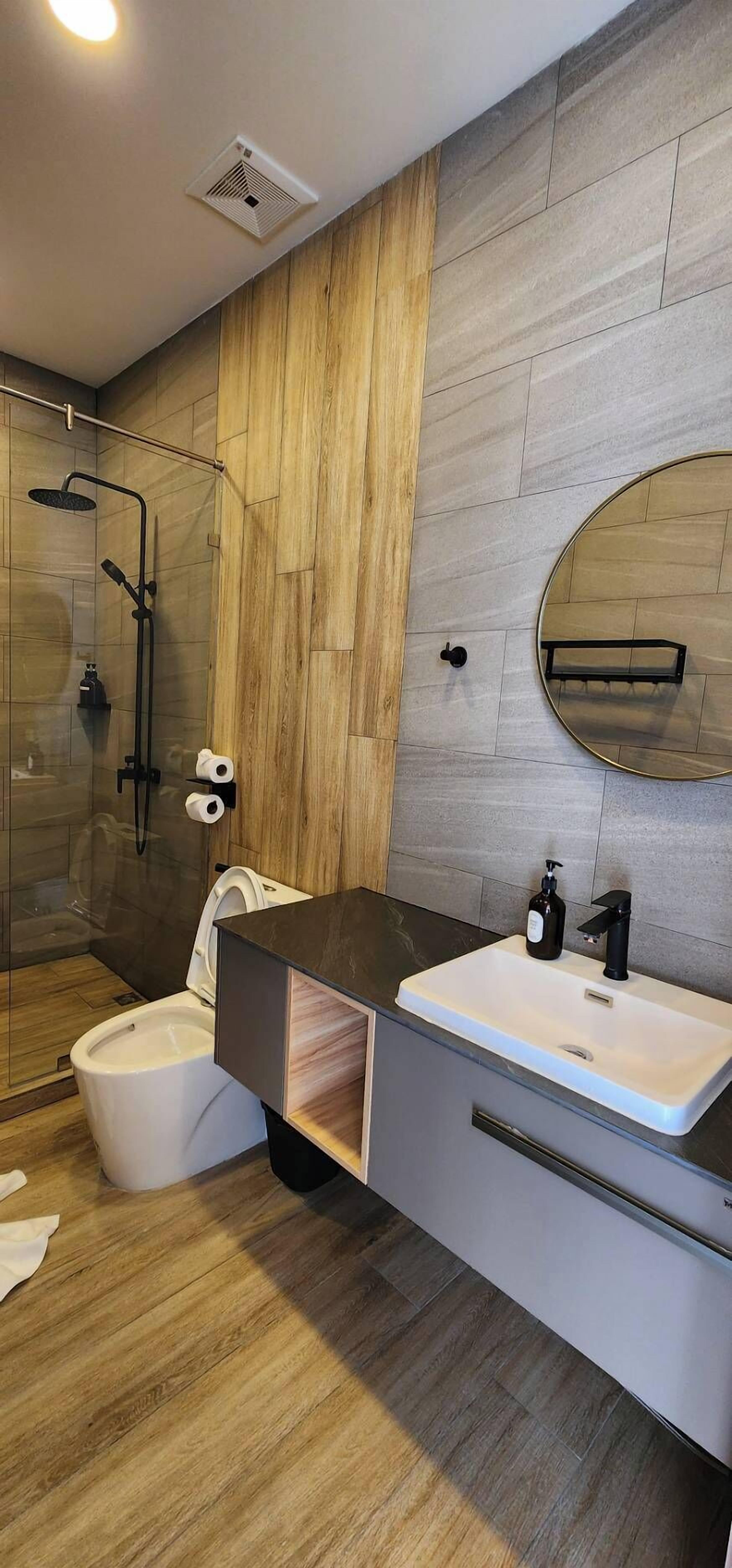 Uma casa de banho moderna com chuveiro, sanita e lavatório.