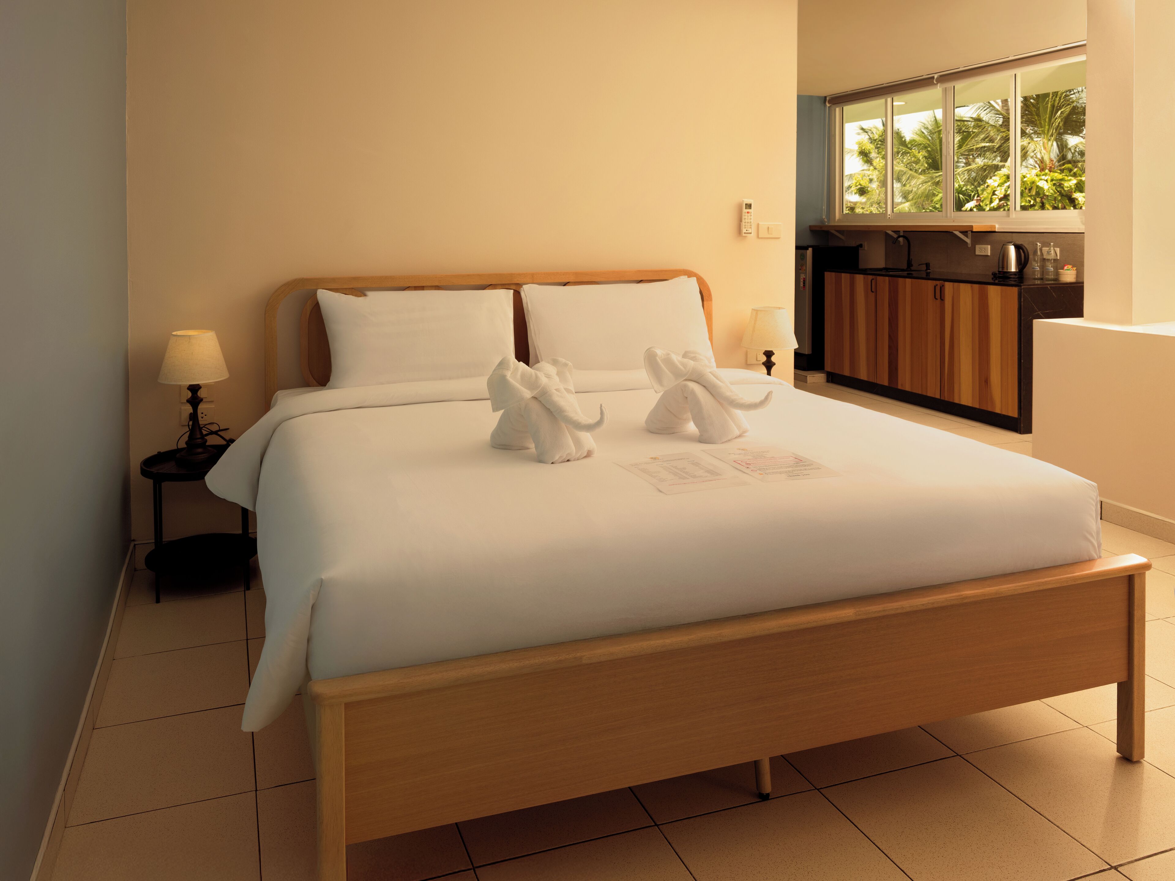 A neatly made bed with white linens and two white towels arranged in a decorative manner.
