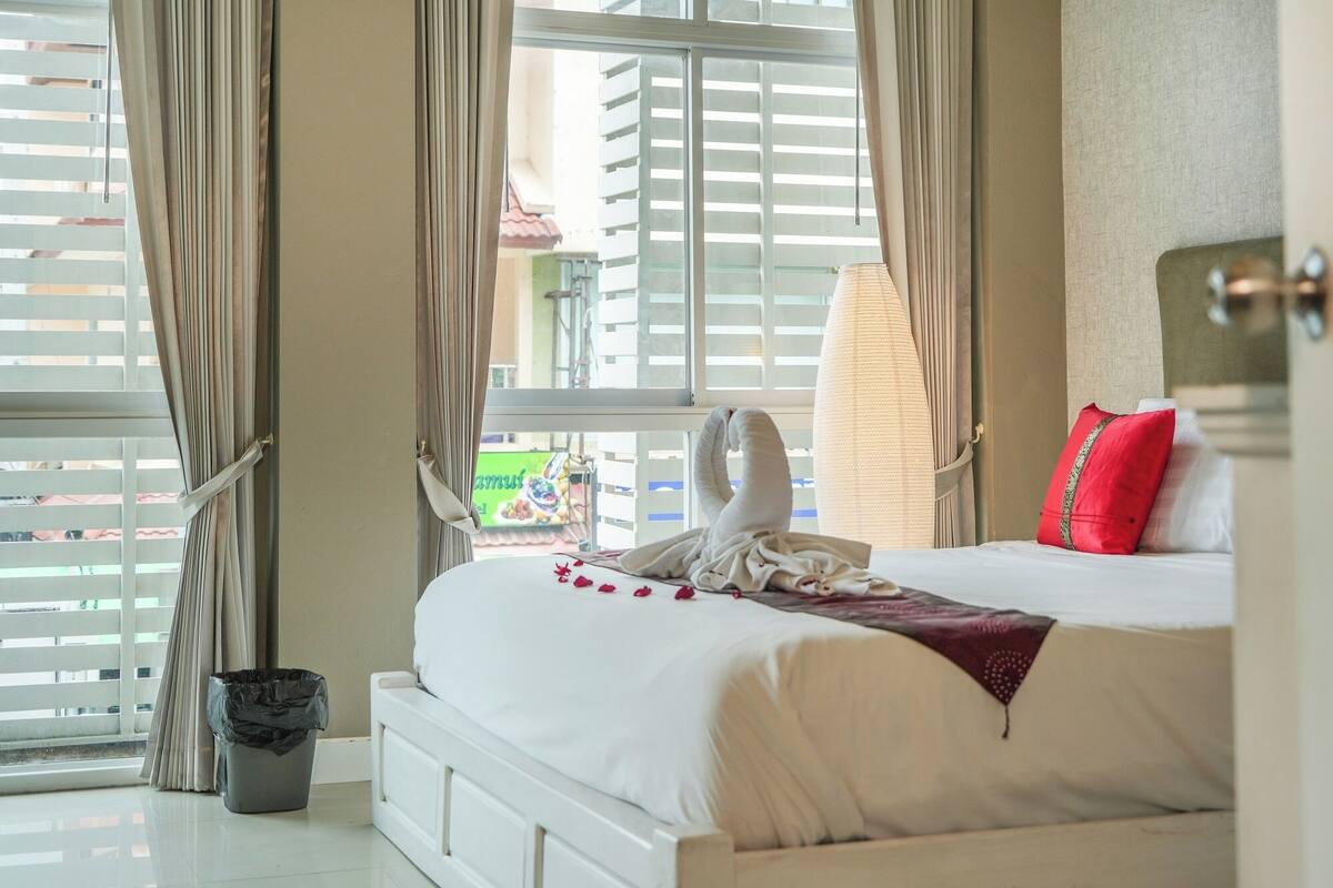 A hotel room with a bed, curtains, a window, and a view of the outside.