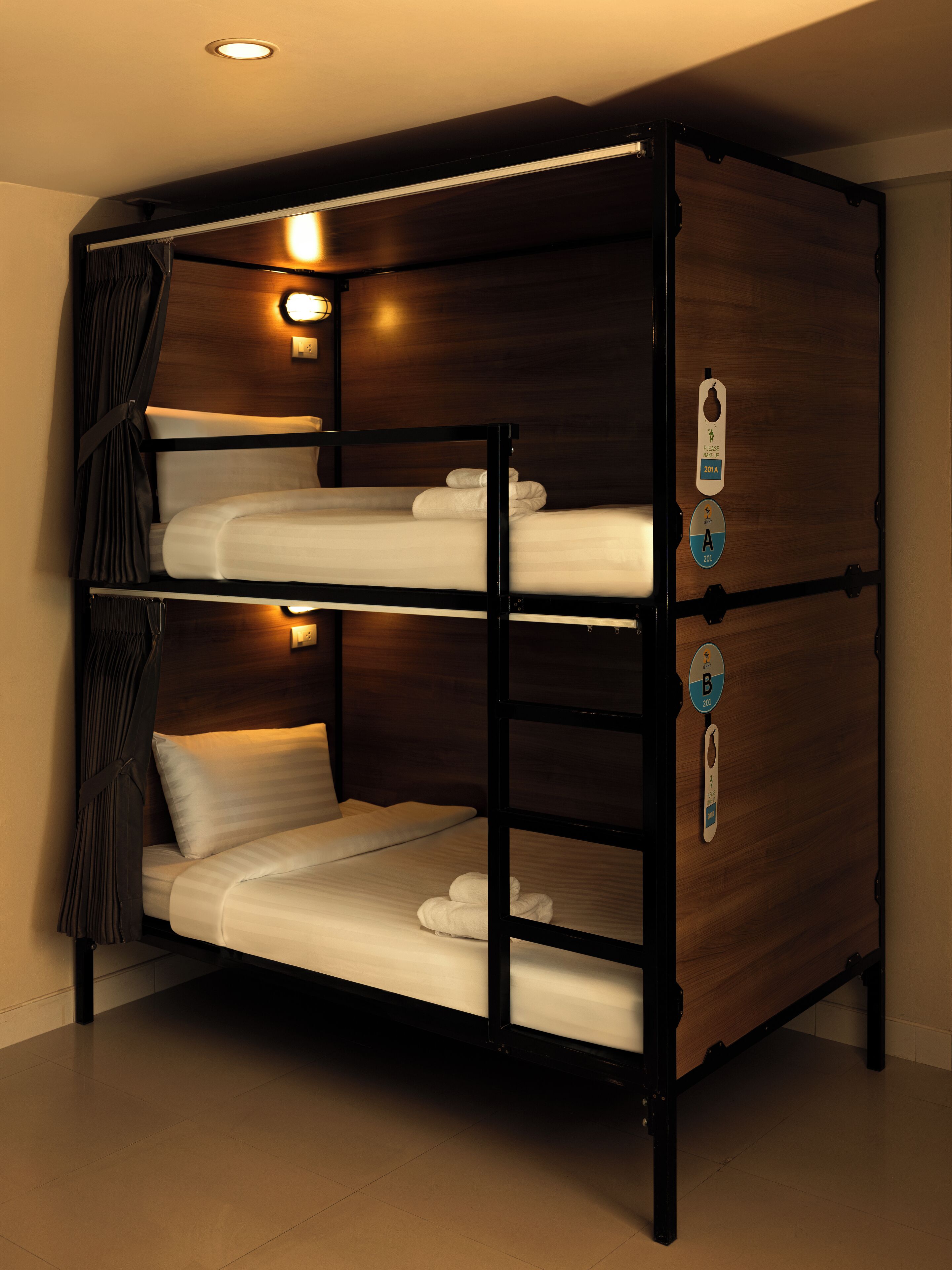 A bunk bed with three levels, each with a pillow and a blanket. There are two light fixtures on the upper level.