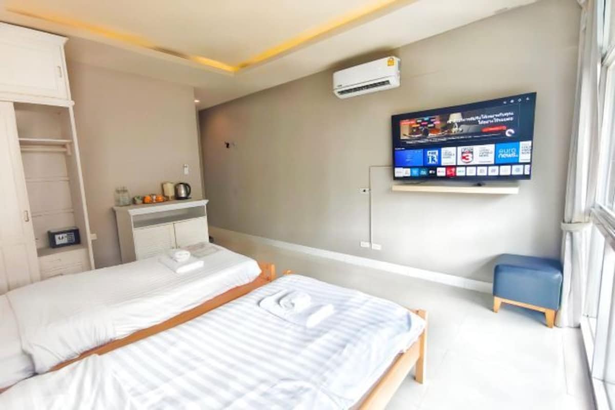 A modern hotel room with a bed, a desk, a TV, and a small seating area.