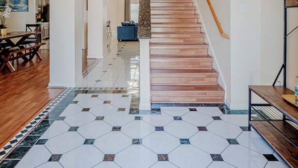 A spacious hallway with a wooden staircase, a chandelier, and a potted plant. - Beautiful and Very Spacious house 6 bed/3.5 baths (Round Rock)