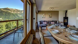 Un comedor con vistas a las montañas, un sofá y una mesa lista para comer.
