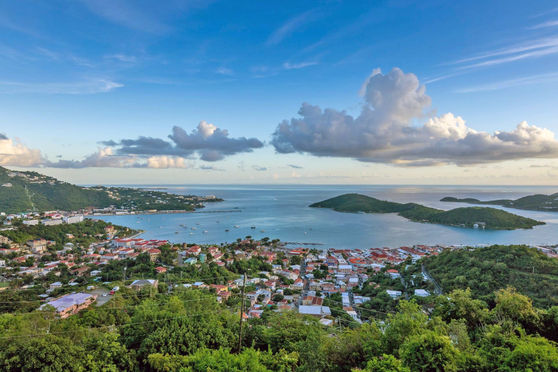 A coastal town with a view of the sea, surrounded by greenery and hills.