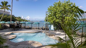 A pool area with a view of the ocean, surrounded by palm trees and a fence. - Beachfront St Thomas Getaway - Family Friendly Resort Condo - Sleeps 8 (St. Thomas)