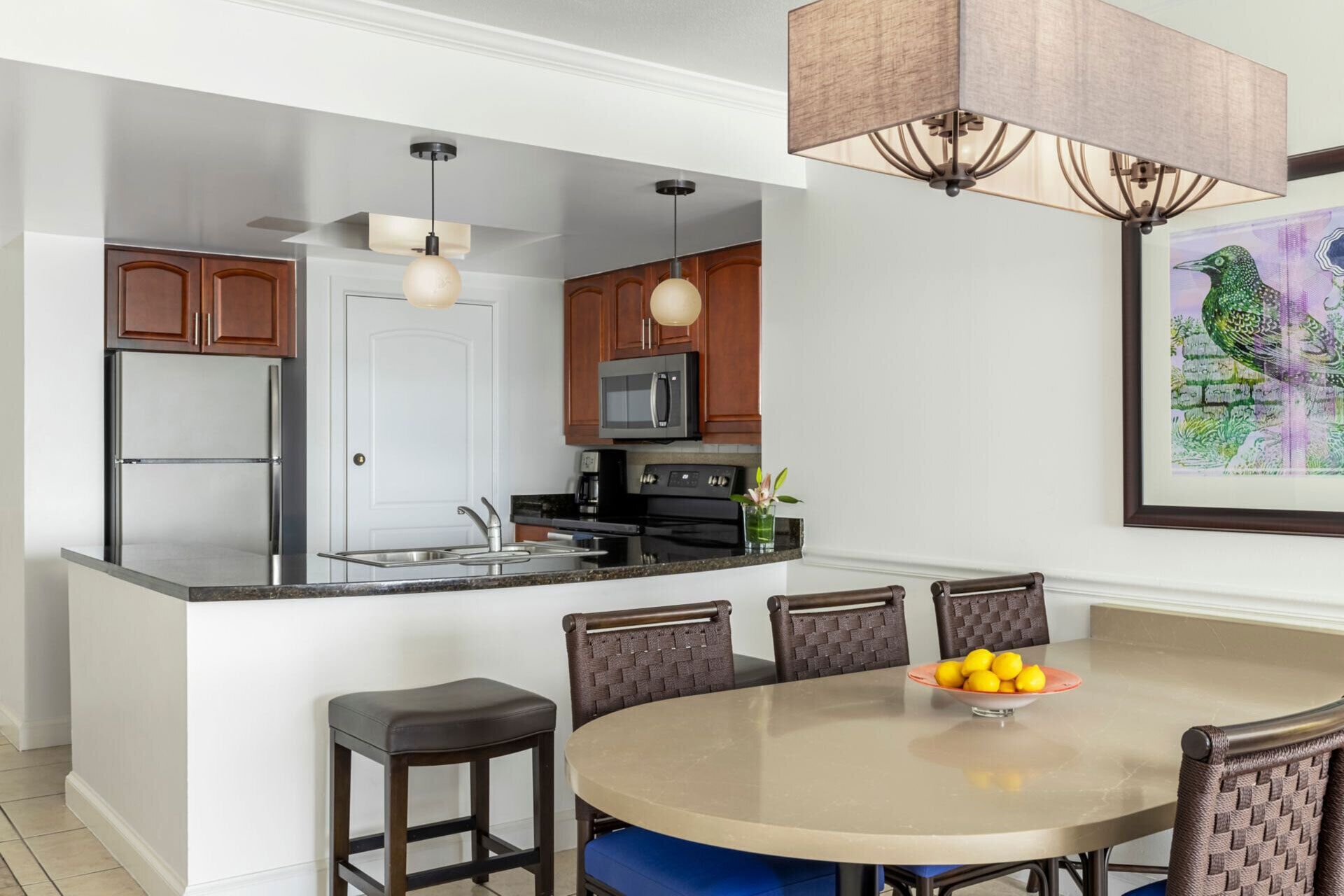 A modern kitchen with a central island, stainless steel appliances, and a dining area with a round table and chairs.