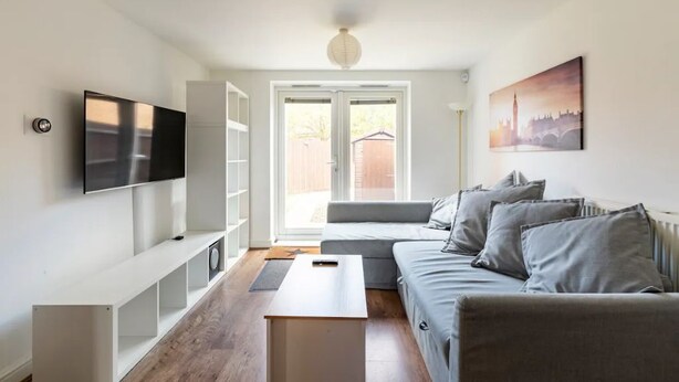 A modern living room with a sofa, TV, and artwork.