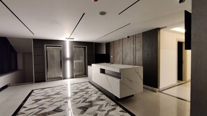 Un moderno vestíbulo de hotel con piso de mármol, una recepción y un espejo grande.