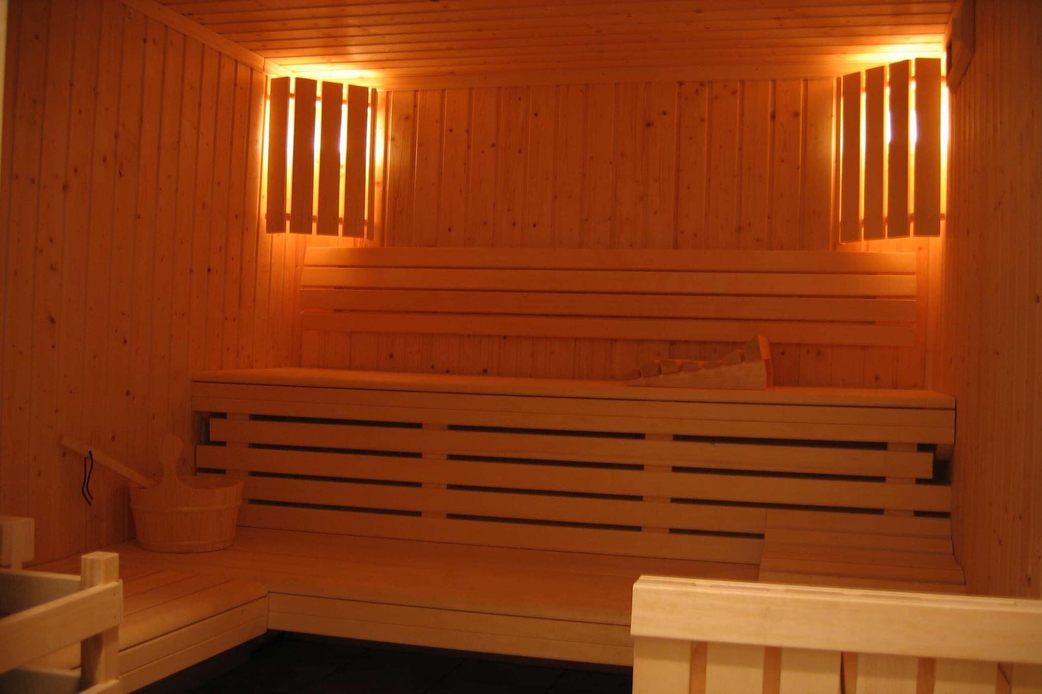 Un sauna avec des bancs en bois et une banquette, des murs en bois et une banquette avec une serviette.