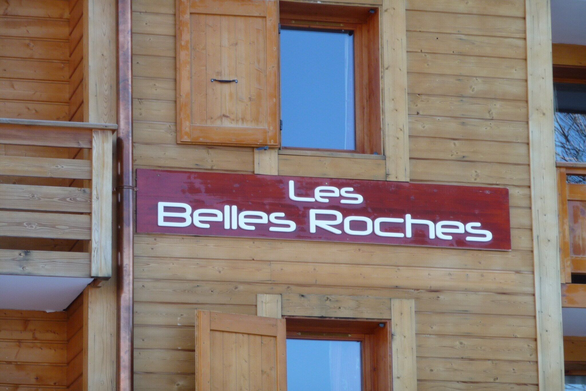 Een houten gebouw met een bord waarop 'Les Belles Roches' staat.