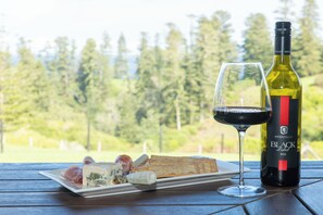 A table with a bottle of wine, a glass of wine, and a plate of cheese and crackers.