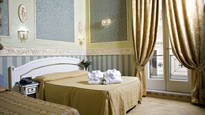 A hotel room with a bed, a nightstand, a telephone, a vase with flowers, and curtains. - Upper View Suite (Rome)
