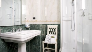A bathroom with a white sink, a shower, and a mirror. - Upper View Suite (Rome)