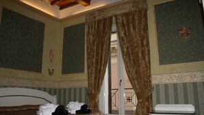 A hotel room with a bed, a small table, and curtains. - Upper View Suite (Rome)
