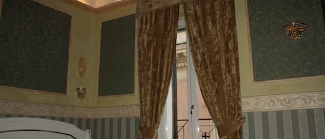 A hotel room with a bed, a small table, and curtains.