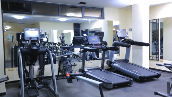 Un gimnasio con diversas máquinas de ejercicio, incluyendo cintas de correr, bicicletas estáticas y elípticas.