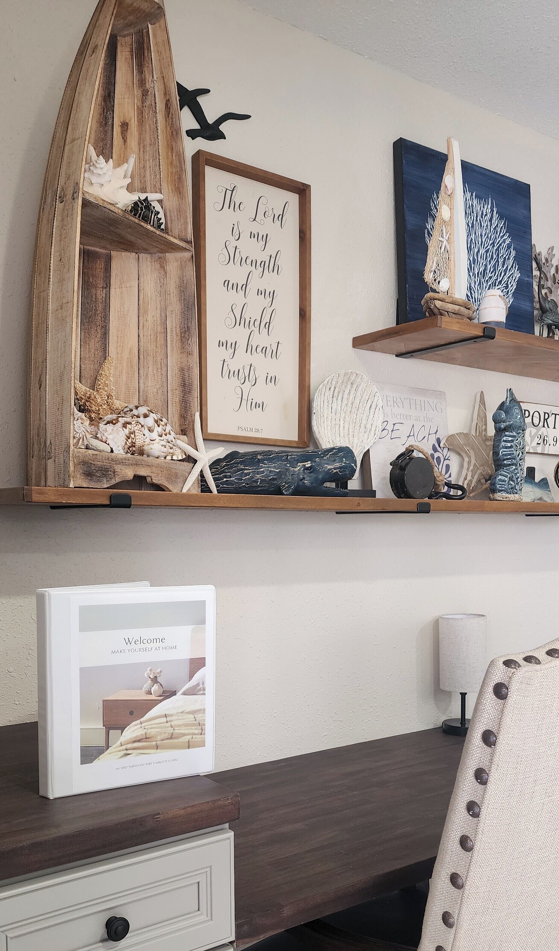 Une étagère en bois ornée d’objets décoratifs, un cadre contenant une citation inspirante et un livre d’accueil.