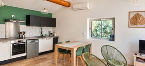 Une cuisine moderne avec un coin repas, comprenant une table et des chaises, un four encastré et une fenêtre donnant sur un espace verdoyant.