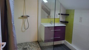 Een badkamer met een douche, wastafel en spiegel.