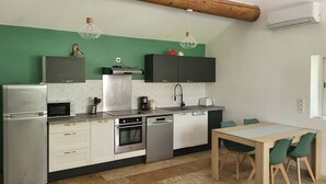 Een moderne keuken met een houten plafond, een eethoek met een tafel en stoelen, en een ingebouwde oven en vaatwasser.